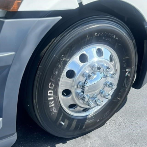 Truck wheel of a 2022 Freightliner Cascadia 126 showing Bridgestone tire and shiny chrome hubcap; partial fender and wheel well visible.