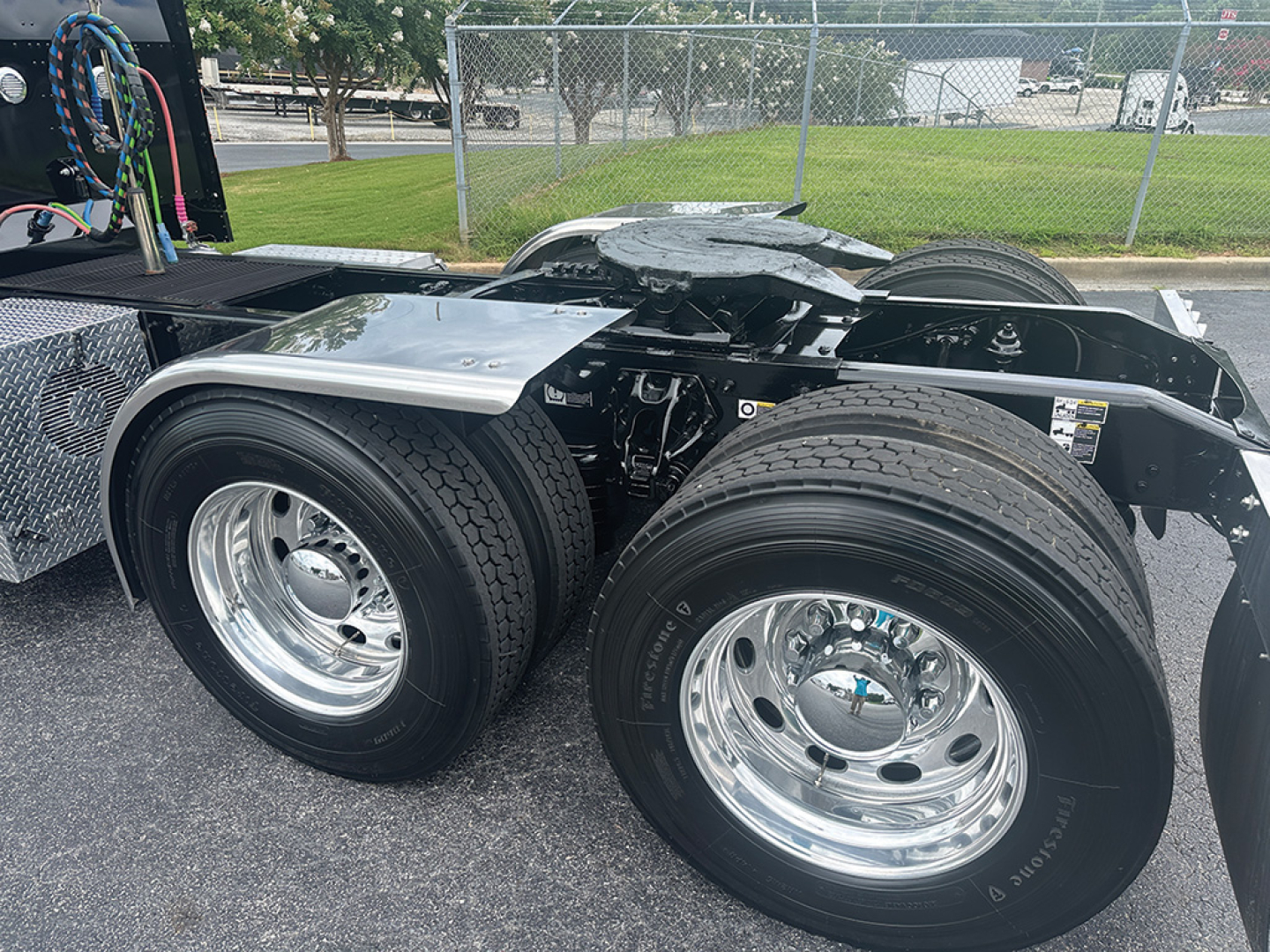 Peterbilt 389 truck rear dual-axle configuration with polished chrome wheels and tire treads visible; auxiliary components and frame visible behind cab area.