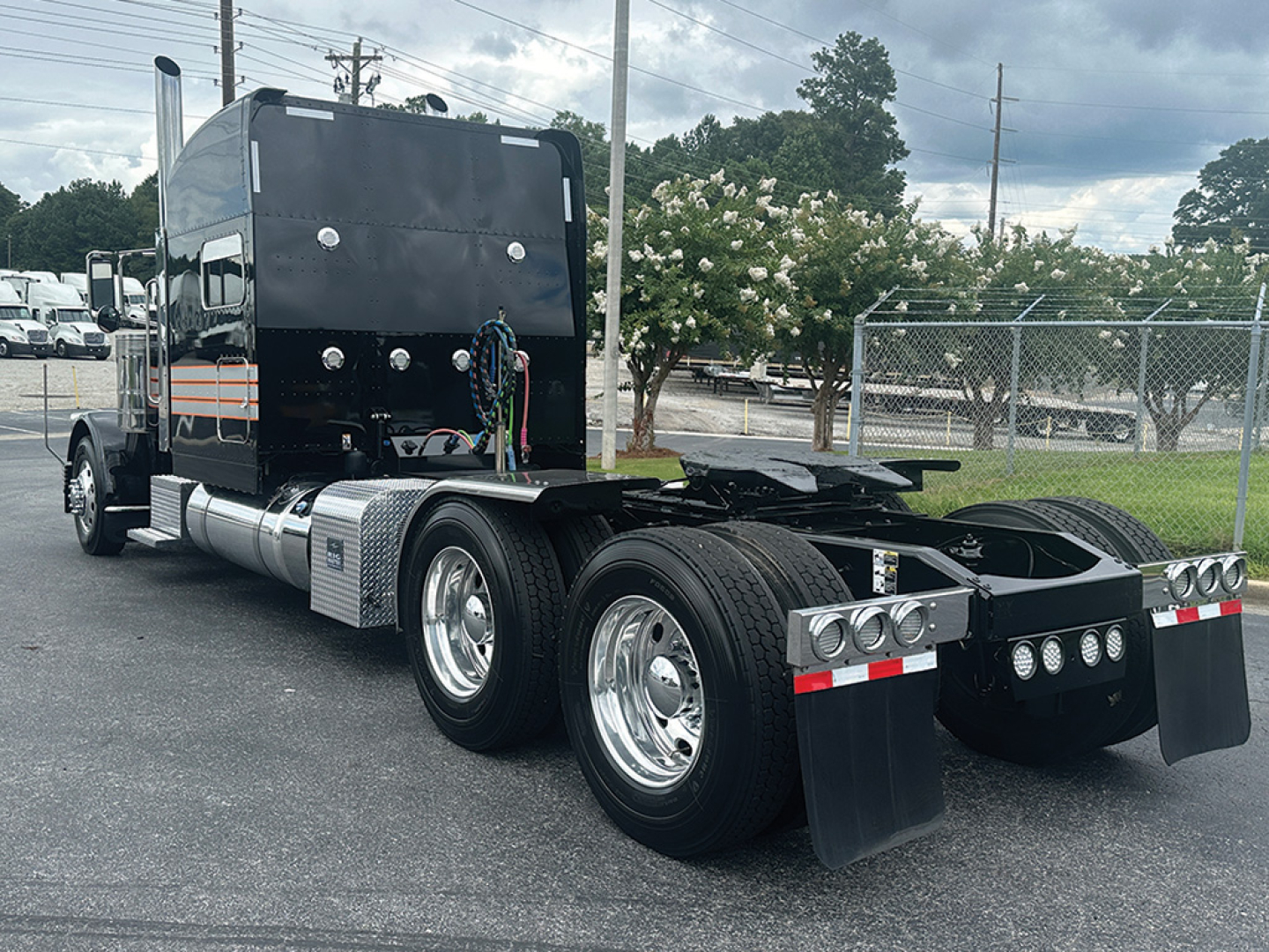 Peterbilt 389 tractor truck view from side rear showing sleeper cab, dual rear axles, chrome wheels, and bumper with lights.