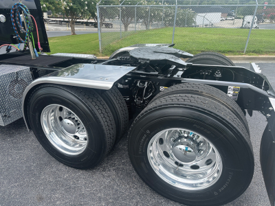 Peterbilt 389 truck rear dual-axle configuration with polished chrome wheels and tire treads visible; auxiliary components and frame visible behind cab area.