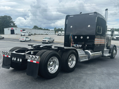 Peterbilt 389 tractor rear view showing dual rear axles, fifth wheel, and polished aluminum steps with air tanks.