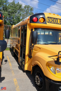 School bus front and side view showing AE Series label, wheel chair lift area, and yellow body with SCHOO B sign on top.