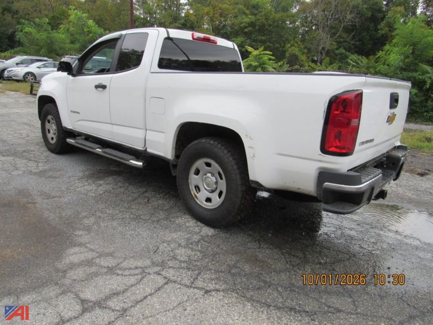 2016 Chevrolet Colorado pickup side rear view showing extended cab, white paint, crew cab doors, short bed, two-tone bumpers, taillights, and chrome side steps.
