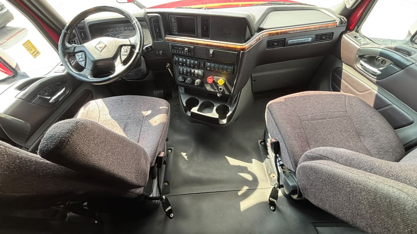 Interior view of a 2022 International LT625 cab showing steering wheel, dashboard with central console, and two front seats.