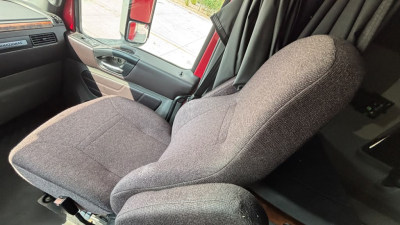 Truck cabin interior with driver seat visible, fabric seat, dashboard and door panel.