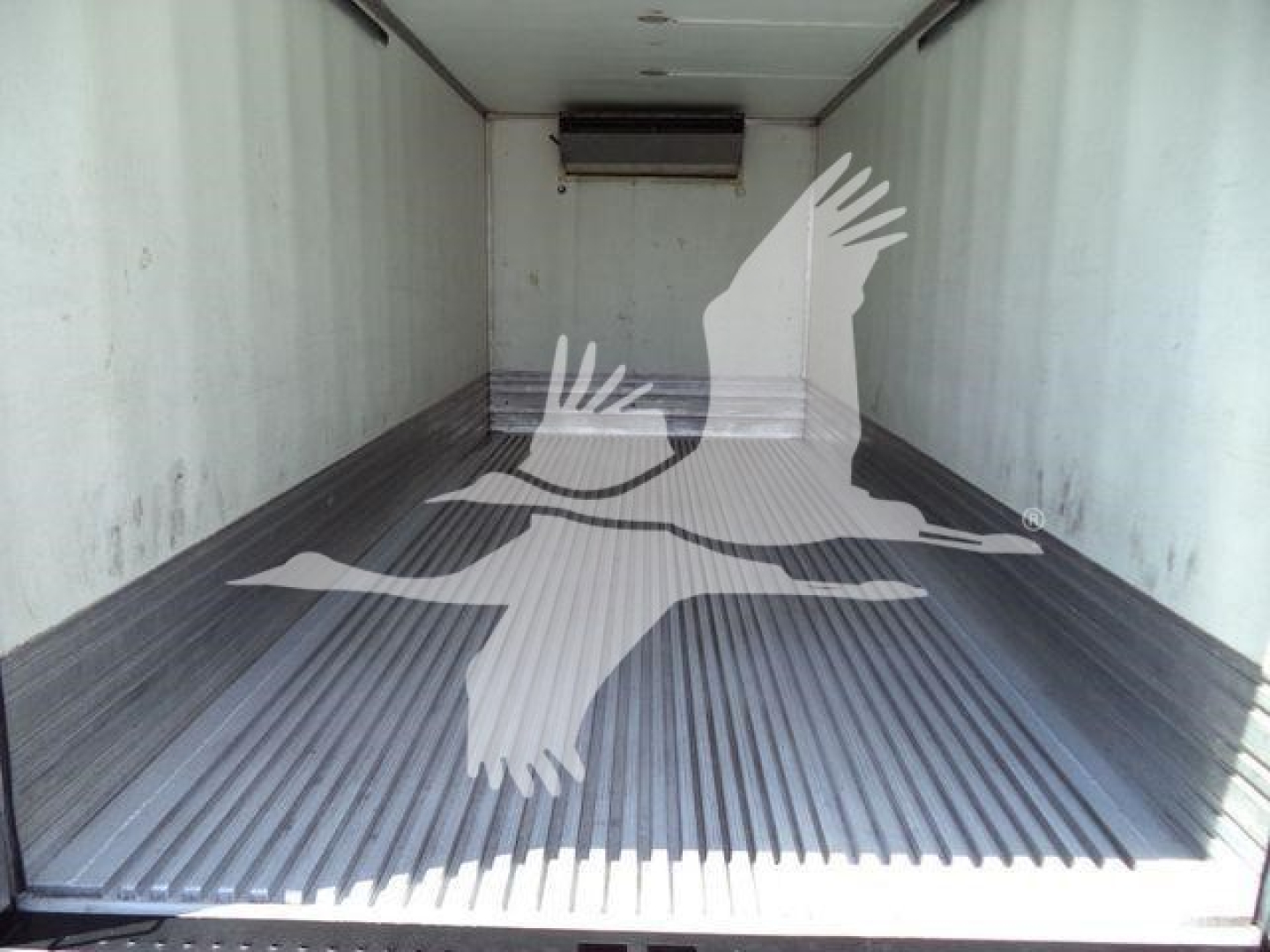 Interior of a refrigerated truck cargo area with ribbed metal floor and overhead air unit visible at the front.