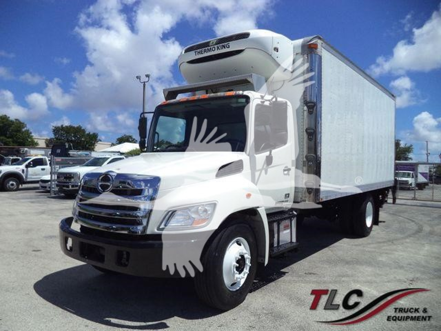 Hino 268A refrigerated truck with a Thermo King unit on top, white cab, blue refrigerated box, daytime outdoor lot.