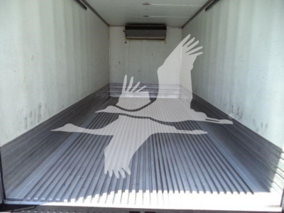 Interior of a refrigerated truck cargo area with ribbed metal floor and overhead air unit visible at the front.