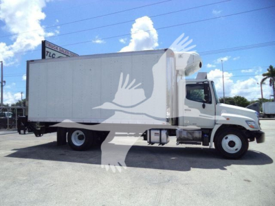 Truck side view: 2015 Hino 268A refrigerated box truck, white cab and box, with refrigeration unit on front of box.