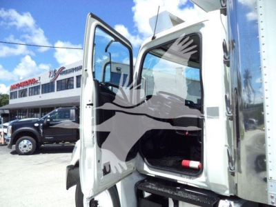 Truck cab doorway open with refrigerated box attached, 2015 Hino 268A, showing driver door open and cargo area entry, dealership lot in background.
