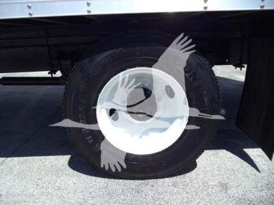 Wheel and tire on a 2015 Hino 268A refrigerated truck, white rim, black tire, undercarriage visible.