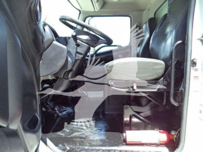 Cab interior of a 2015 Hino 268A with steering wheel, driver seat, and a fire extinguisher mounted behind the front bench.