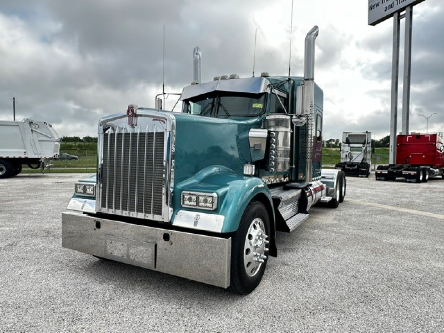 Kenworth W900L truck in teal with chrome grille, front view, showing large bumper and dual exhaust stacks.