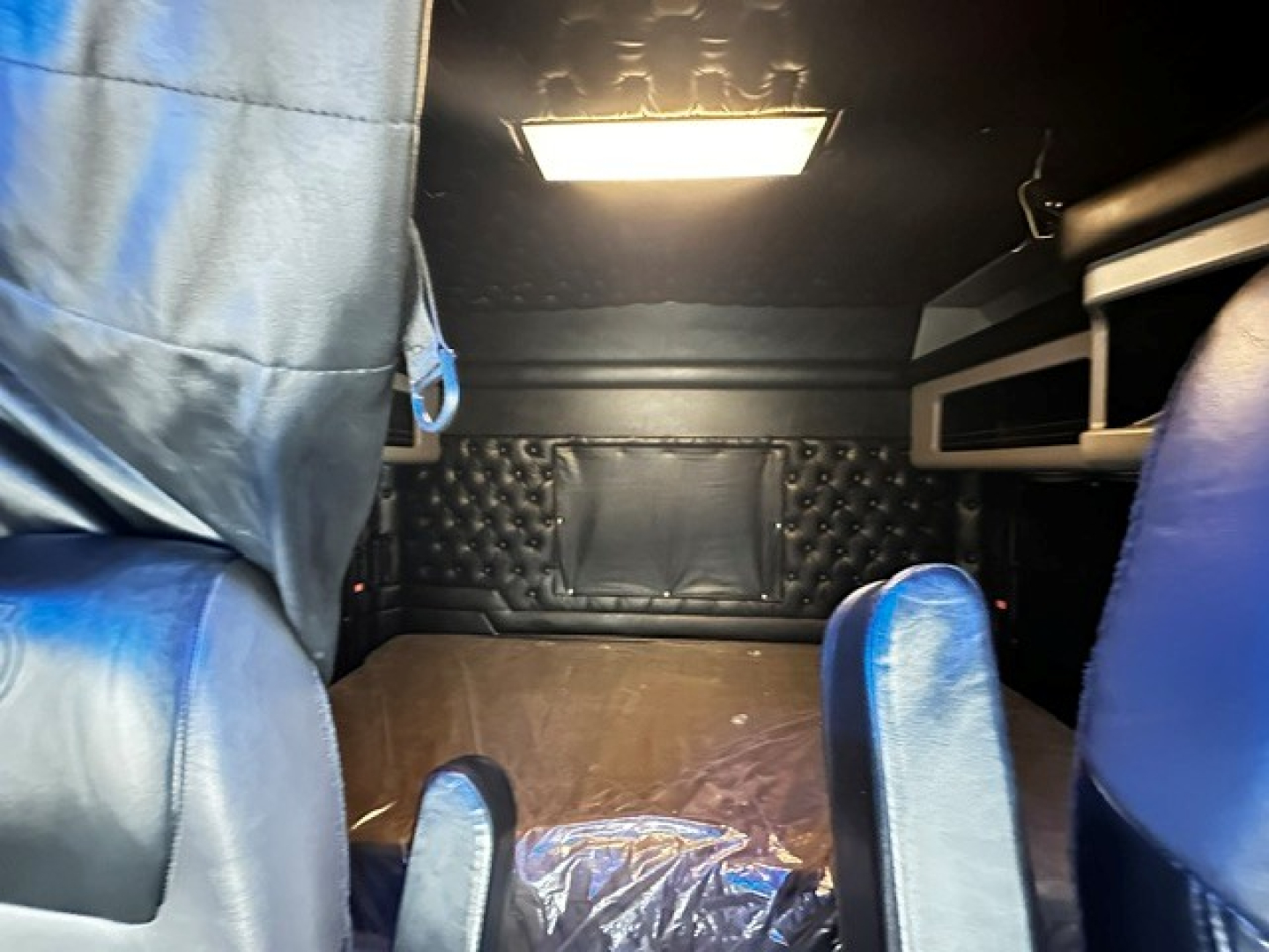 Kenworth W900L sleeper cab interior cargo area showing dark quilted paneling, padded walls, and overhead light.