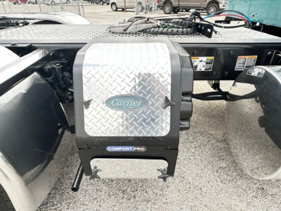 Truck chassis with Carrier fuel/air system access panel and diamond plate cover visible in the engine bay area of a 2022 Kenworth W900L conventional sleeper.