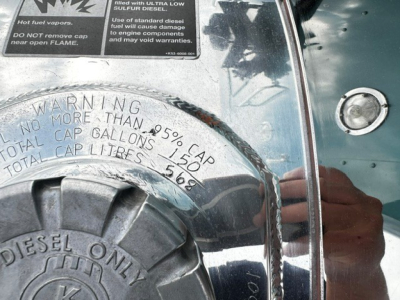 Kenworth W900L engine bay area showing chrome fuel/diesel cap with warnings and label text including warning and numbers.