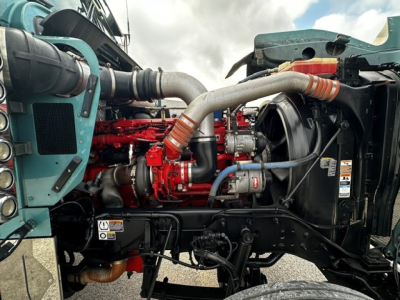 Kenworth W900L engine bay showing red diesel engine with intake piping and surrounding components.