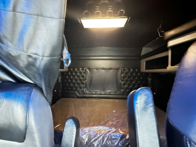 Kenworth W900L sleeper cab interior cargo area showing dark quilted paneling, padded walls, and overhead light.