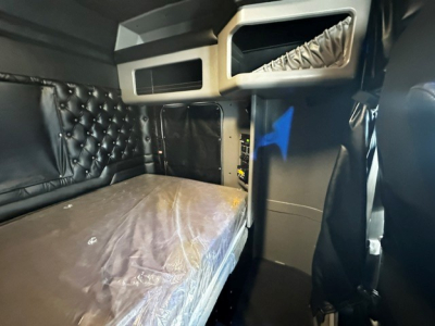 Interior sleeper cab of a Kenworth truck with bunk area and storage compartments visible.