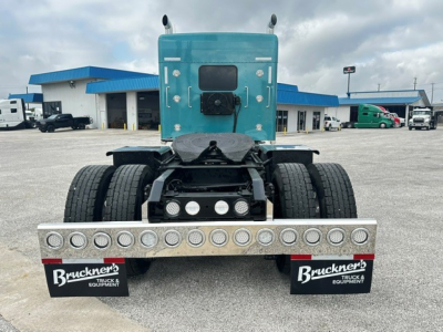 Kenworth W900L tractor rear view showing dual rear axles, aluminum fifth-wheel plate, and bumper with circular light guards.