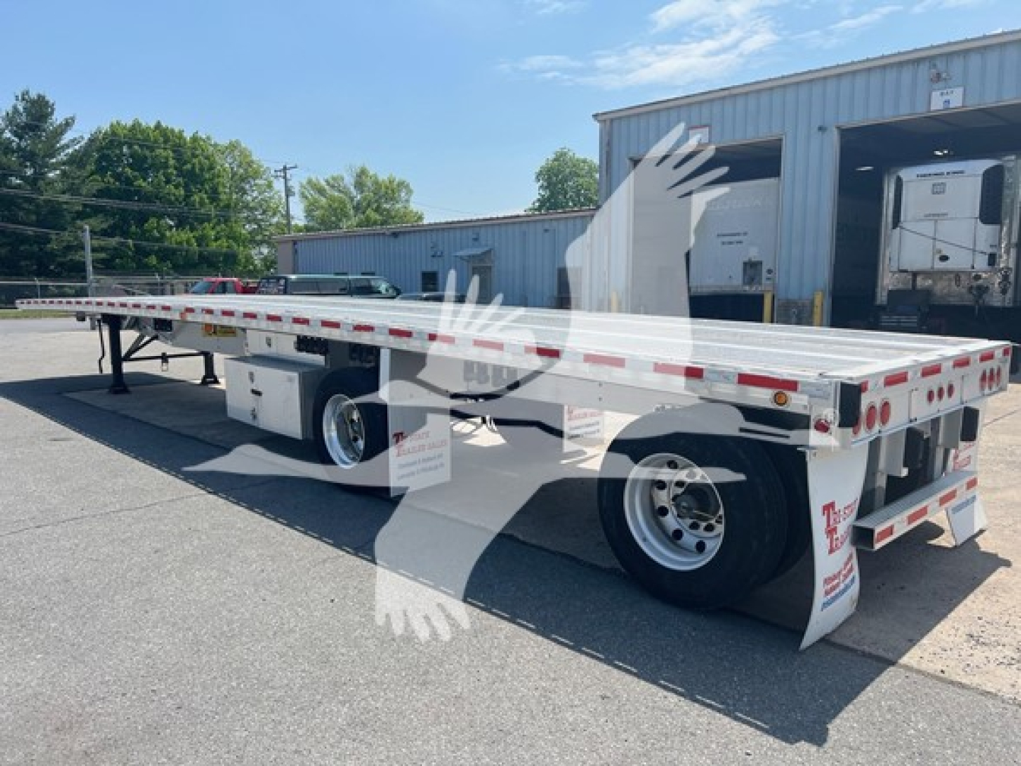 Flatbed trailer showing long aluminum deck with dual axles and rear bumper, white with reflective tape and mud flaps, 2015 Reitnouer Maxmiser trailer.
