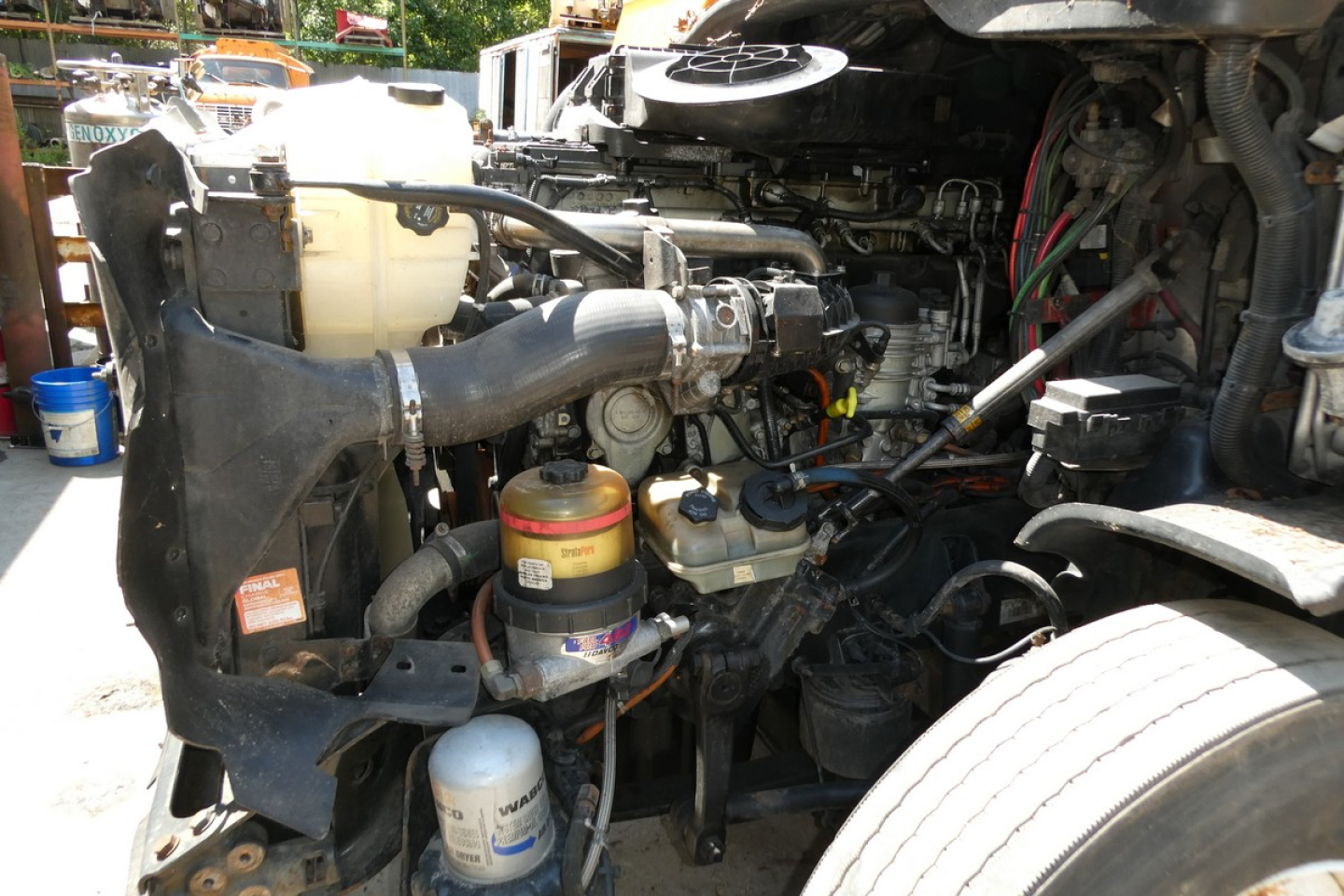 Freightliner Cascadia 125 engine bay showing coolant reservoir, air filter canister, hoses, and various engine components.