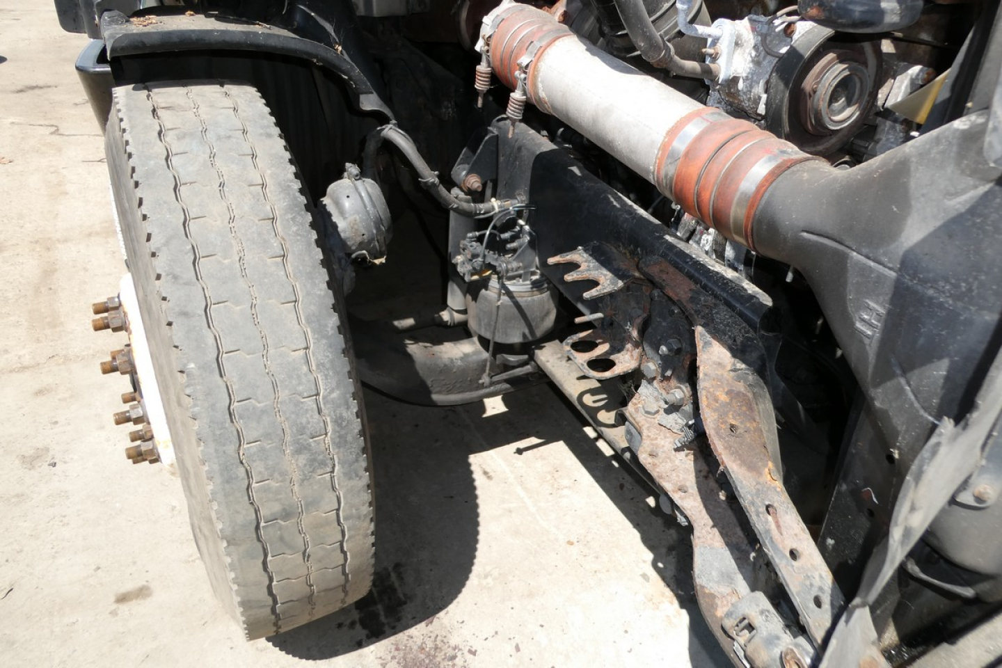 Freightliner Cascadia 125 front left undercarriage showing steering linkage, exhaust, and large front tire with wear.
