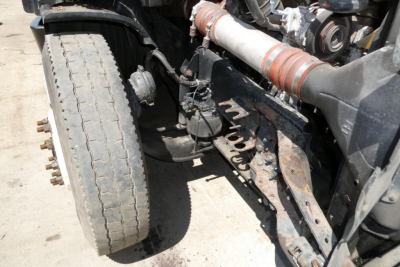 Freightliner Cascadia 125 front left undercarriage showing steering linkage, exhaust, and large front tire with wear.
