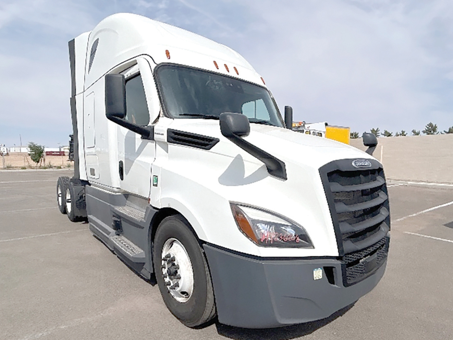 White Freightliner Cascadia126 tractor in a parking lot with sleeper cab and black grille.