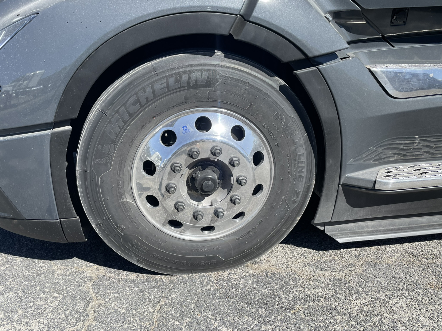 Wheel and front fender of a Volvo VNL truck showing Michelin tire and steel wheel with lug nuts.