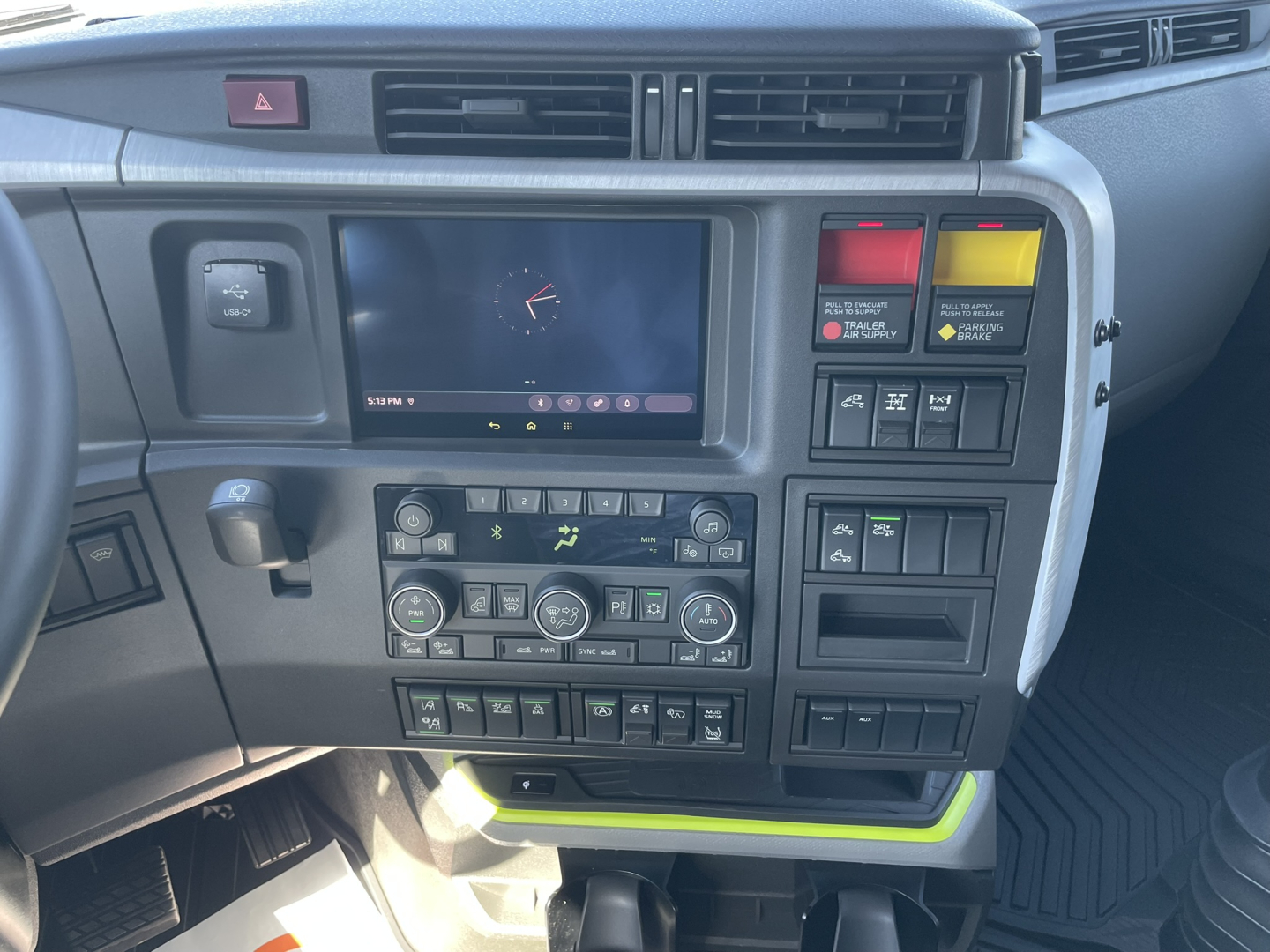 Volvo VNL64T860 truck cab dashboard showing center touchscreen, climate controls, and various buttons viewed from driver's seat.