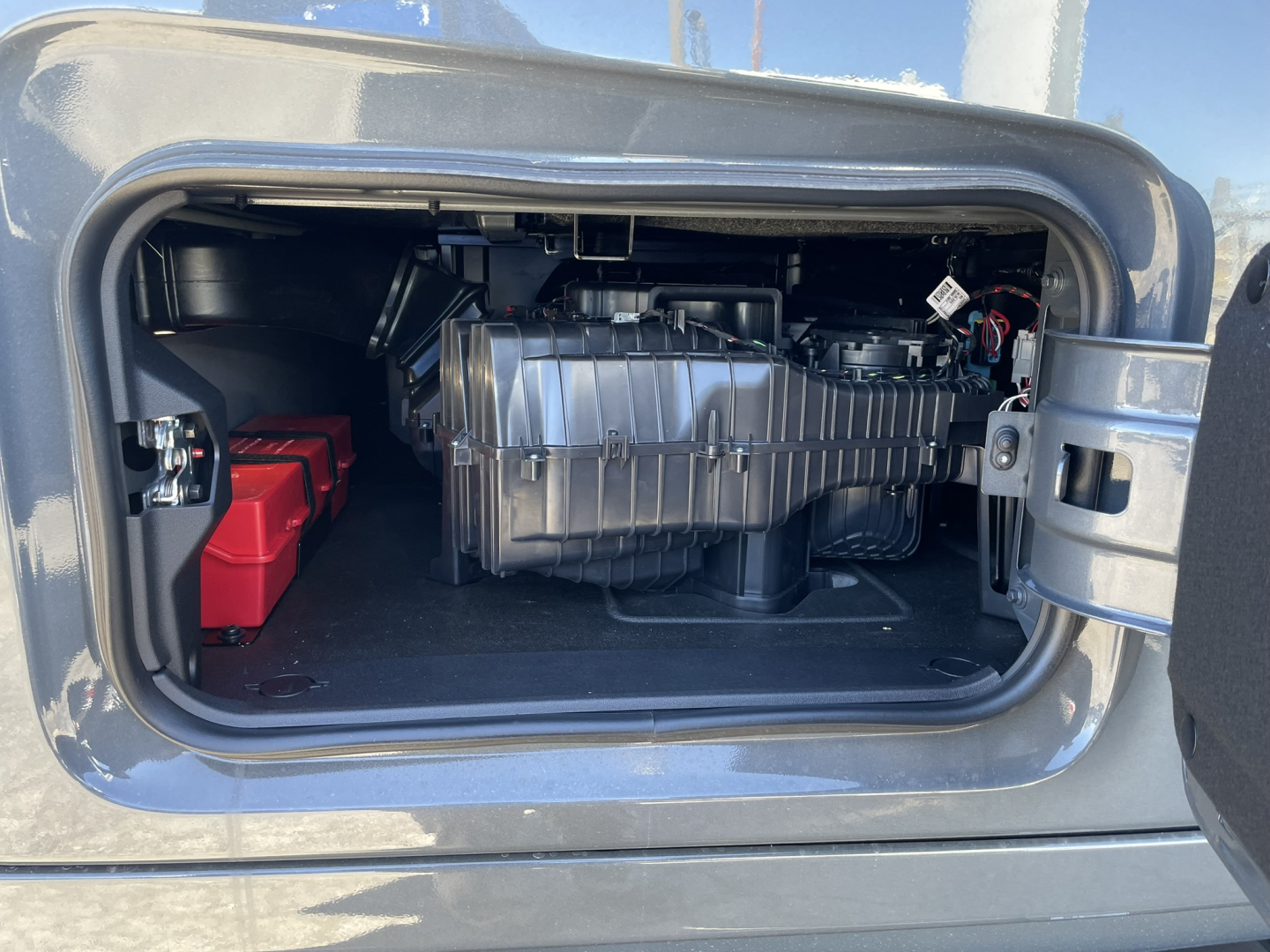 Volvo VNL64T860 cab area showing engine bay/storage with a large silver component and red battery pack visible.