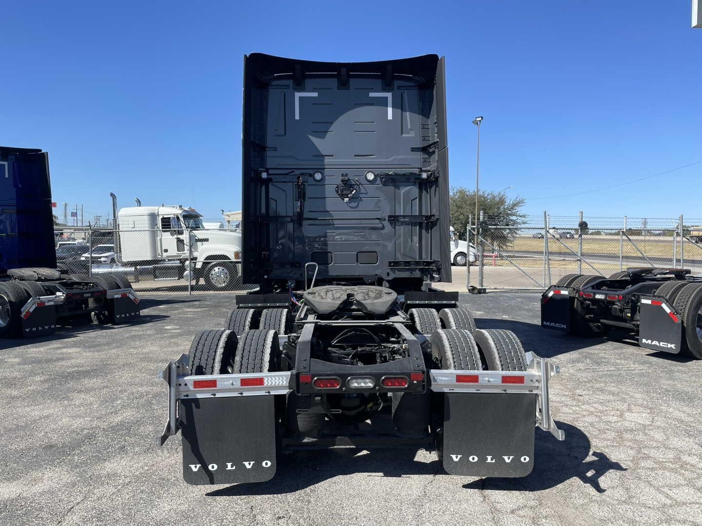Volvo VNL64T860 tractor rear view showing dual rear axles and mud flaps with VOLVO branding.