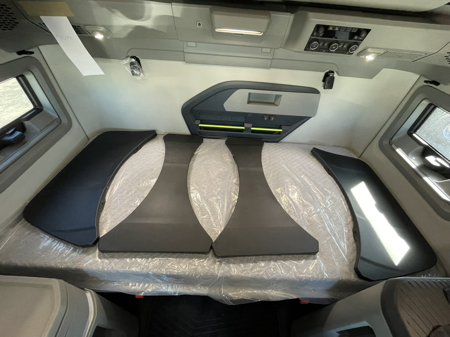 Volvo VNL64T860 sleeper cab interior showing seating/bed area with cushions and overhead panels.