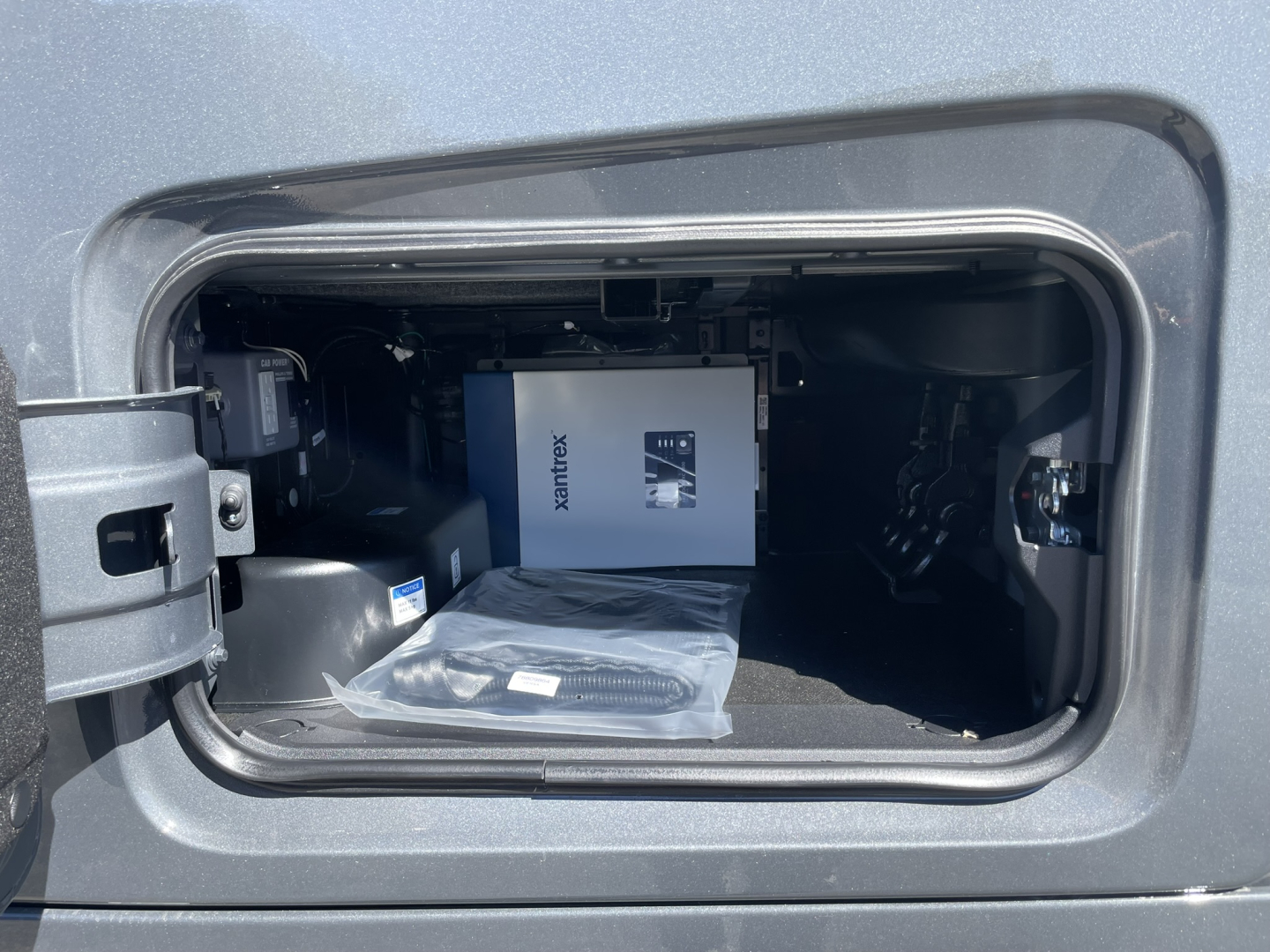Volvo VNL64T860 truck cab storage compartment showing a boxed item and a black cable in the open side hatch.
