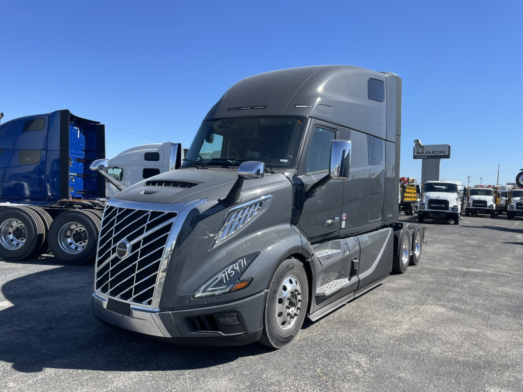 Volvo VNL64T860 truck in a parking lot with shadow; front grille, headlights, and badge visible