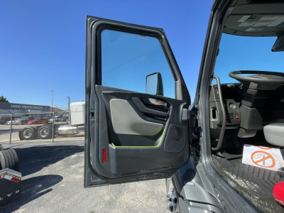 Volvo truck cab door open showing interior and door panel with speaker grill and window, blue sky in background.