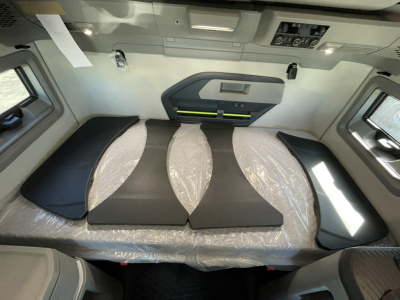 Volvo VNL64T860 sleeper cab interior showing seating/bed area with cushions and overhead panels.