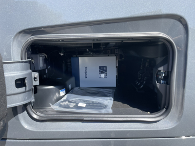 Volvo VNL64T860 truck cab storage compartment showing a boxed item and a black cable in the open side hatch.