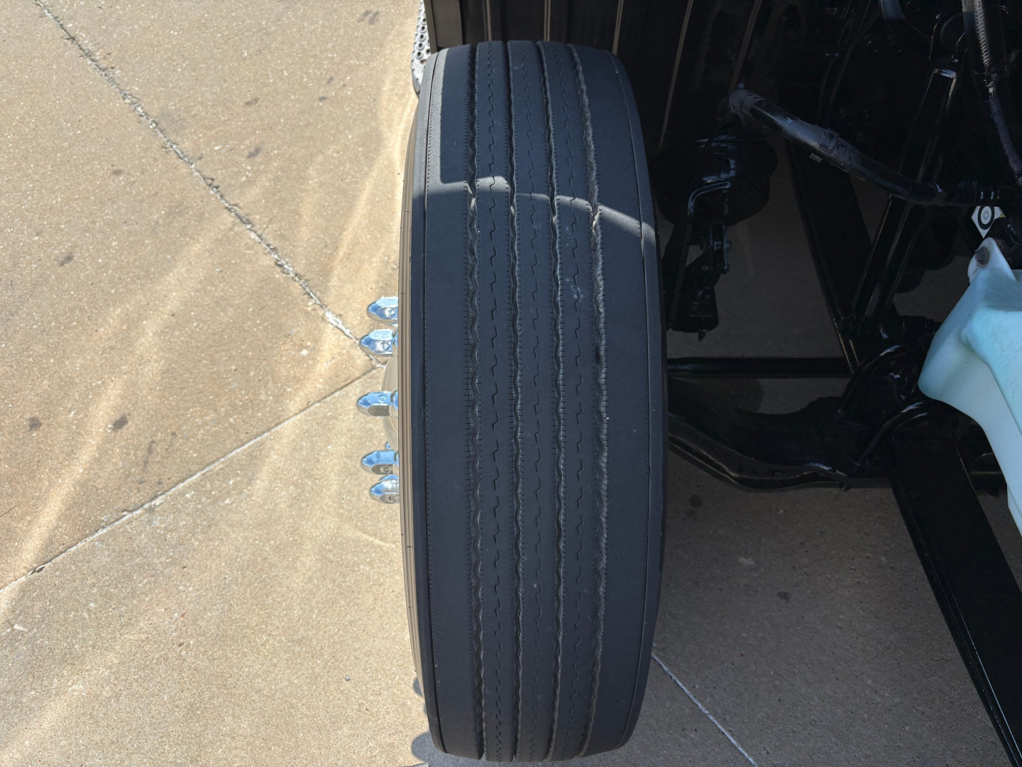 Wheel viewed from side of 2022 Peterbilt 579 truck showing a single Michelin-style tire with multiple grooves and surrounding chassis.