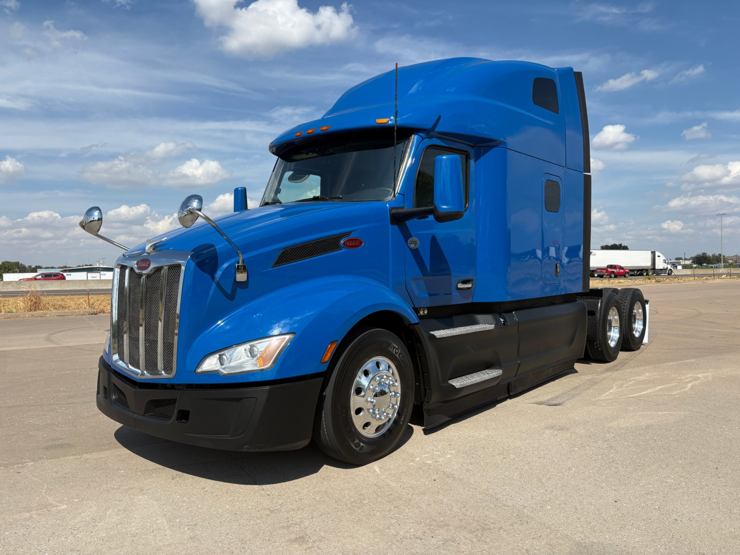 Peterbilt 579 conventional sleeper truck blue exterior side view showing long hood and chrome wheels.