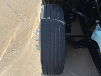 Wheel viewed from side of 2022 Peterbilt 579 truck showing a single Michelin-style tire with multiple grooves and surrounding chassis.