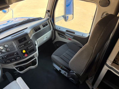 Peterbilt 579 truck cab interior showing driver seat and dashboard with controls and storage compartments.
