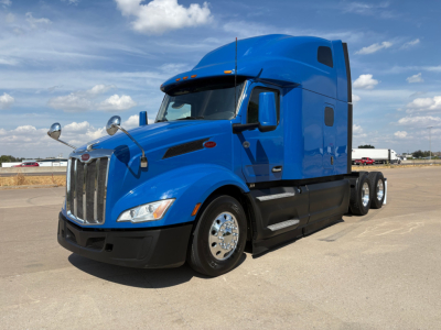 Peterbilt 579 conventional sleeper truck blue exterior side view showing long hood and chrome wheels.