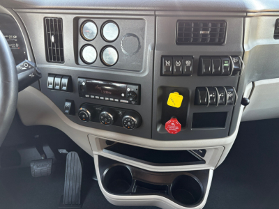 Peterbilt instrument cluster and dashboard view inside cab showing gauges, steering column, air vents, controls, and cup holders.