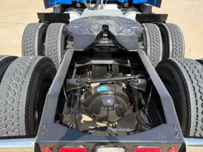 Dual rear axles of a Peterbilt 579 tractor showing the differential housing and suspension. View from behind the cab with fifth wheel area and frame rails visible.