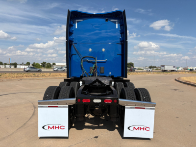 Peterbilt 579 tractor rear view showing blue cab, dual rear axles, with MHC branded mud flaps and rear underride area.