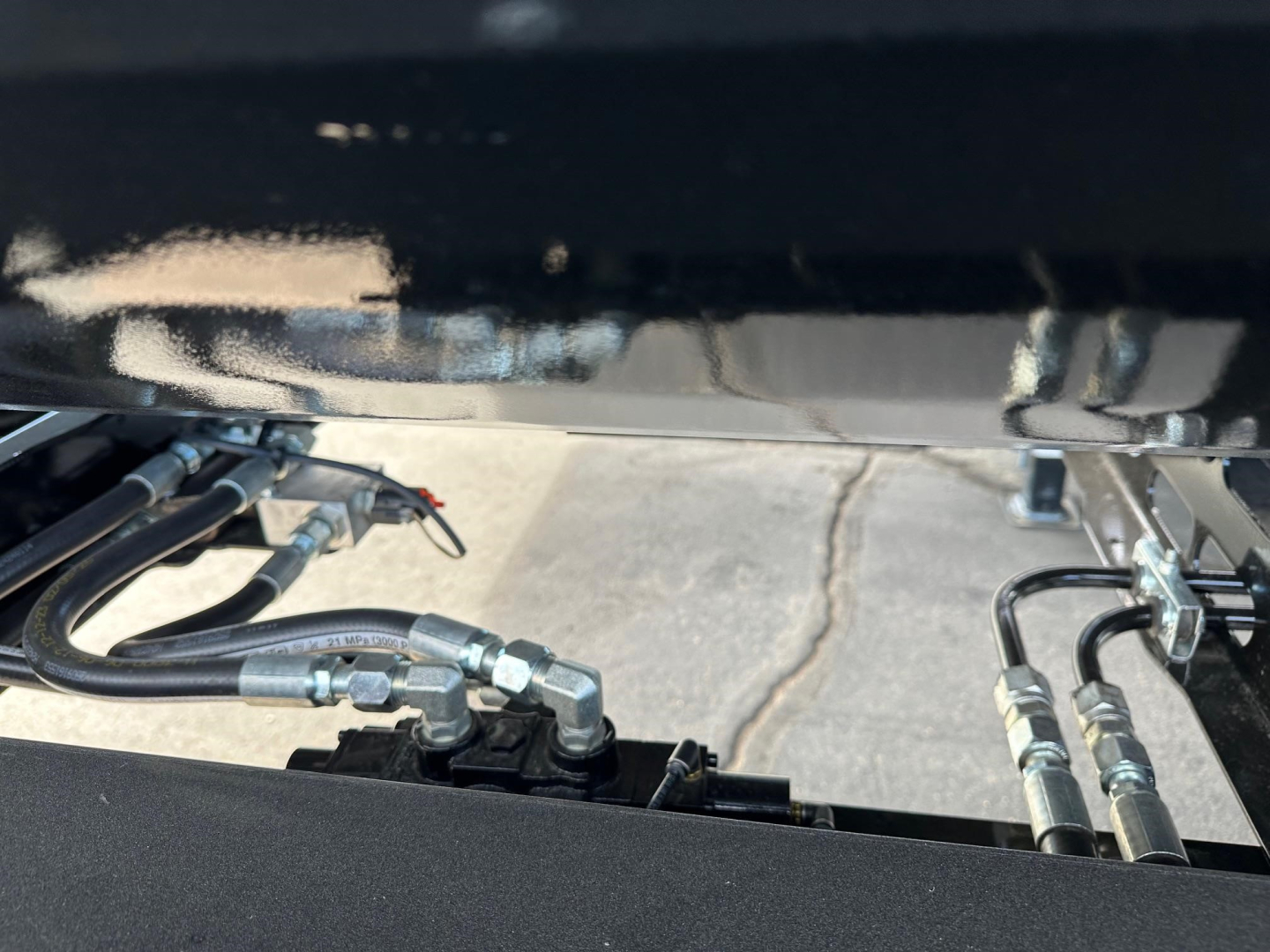 Manac combo drop deck trailer chassis view showing hydraulic hoses and fittings underframe and connectors.