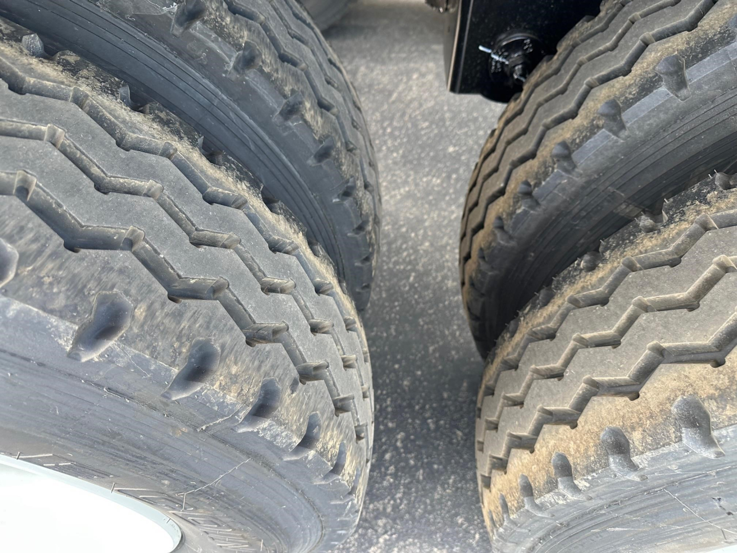 Trailer wheel close-up showing dual rear axles with heavy-duty tires for Manac drop deck trailer.