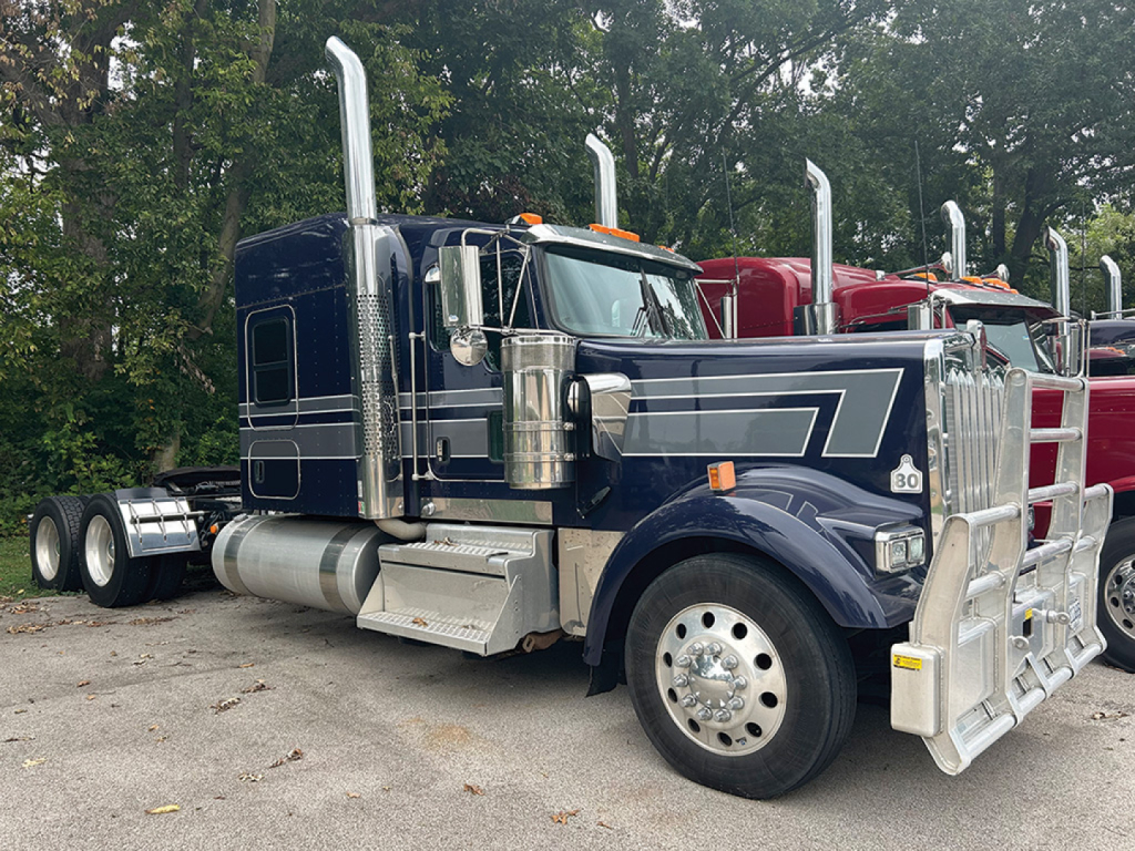 Kenworth W-900L AeroCab tractor-trailer shown in dark blue with chrome exhaust stacks and sleeper cab.